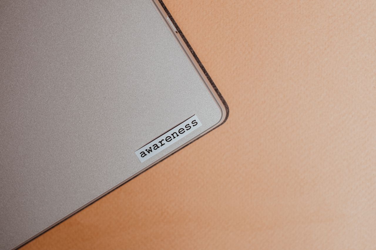 Detailed view of a beige laptop displaying an awareness sticker, highlighting mindfulness and digital organization.